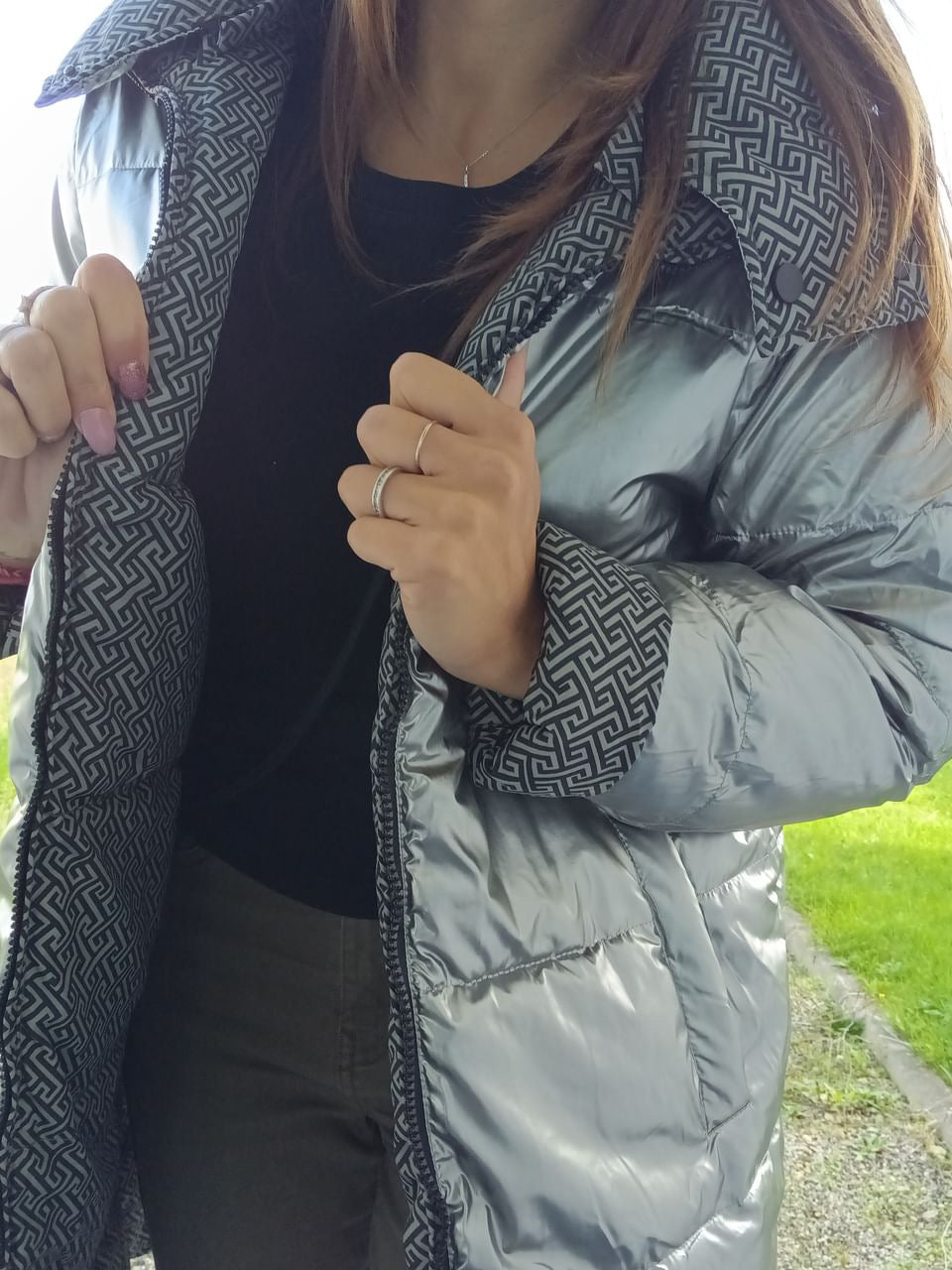 Woman modeling a reversible silver quilted waterproof coat with geometric lining from Le Petit Placard