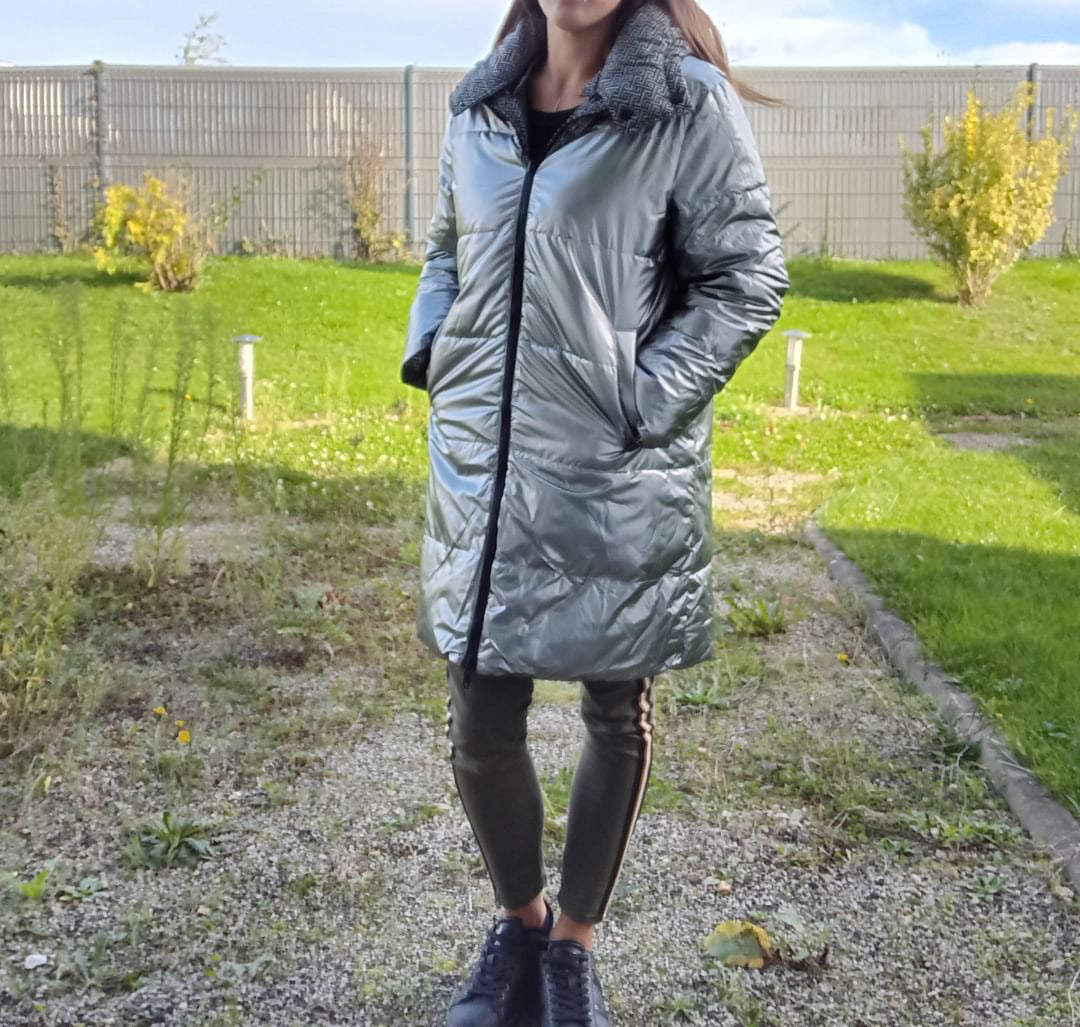 Woman wearing a long silver quilted reversible waterproof coat outdoors, Le Petit Placard