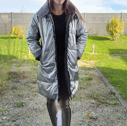 Woman wearing a long reversible silver quilted waterproof coat outdoors from Le Petit Placard.