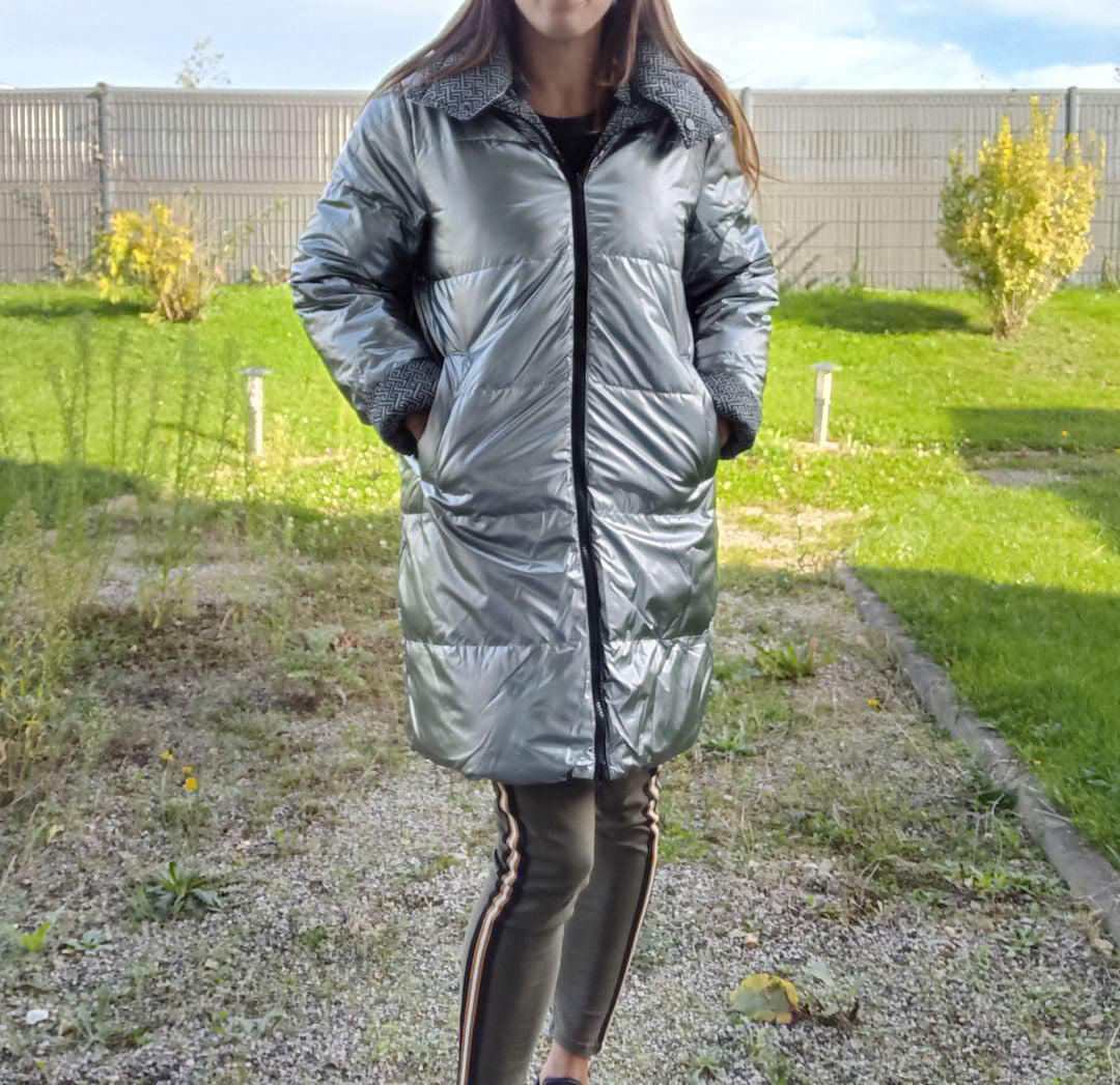 Woman wearing a long reversible silver quilted waterproof coat outdoors, Le Petit Placard