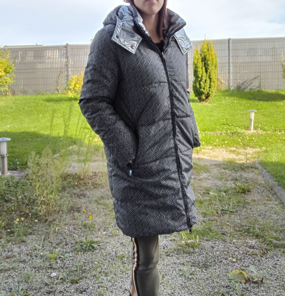 Woman wearing long reversible grey quilted waterproof coat outdoors, Le Petit Placard fashion