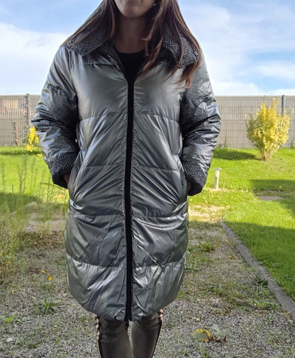 Woman wearing a long reversible silver quilted raincoat in outdoor garden, Le Petit Placard