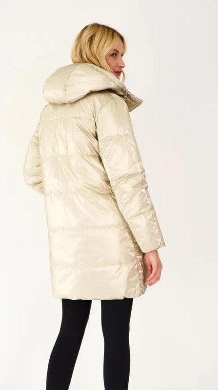 Woman wearing a long reversible gold quilted waterproof coat from Le Petit Placard