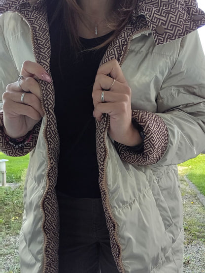 Woman wearing a reversible long quilted beige and brown patterned waterproof coat outdoors
