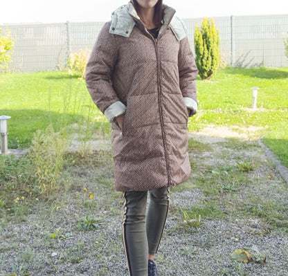 Woman wearing Escandelle reversible long waterproof quilted brown coat, outdoor setting