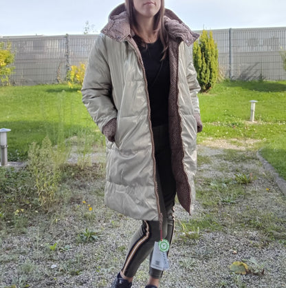 Woman wearing a long reversible waterproof quilted gold coat from Le Petit Placard outdoors