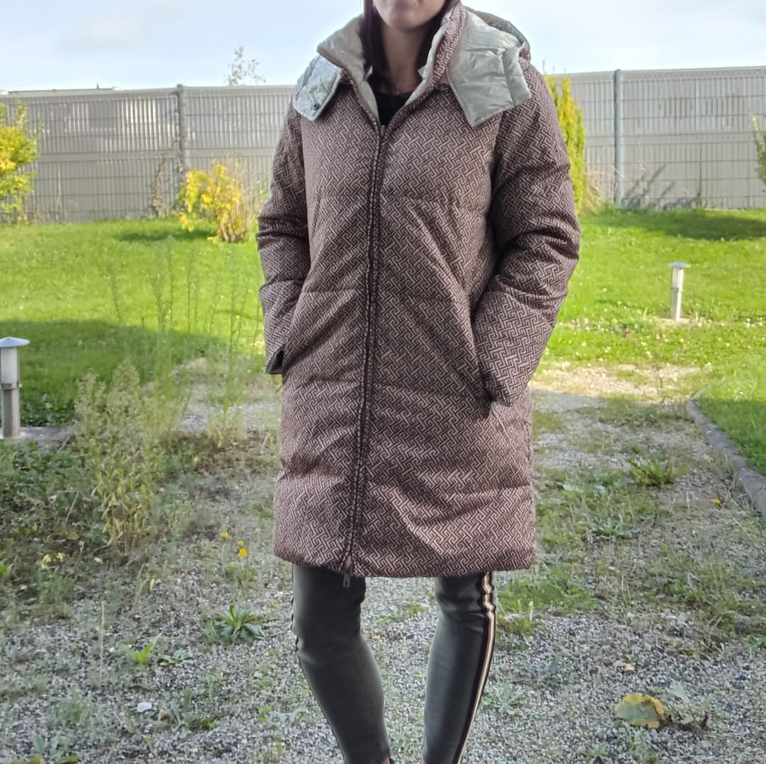Woman wearing a brown reversible quilted waterproof long coat outside, Le Petit Placard