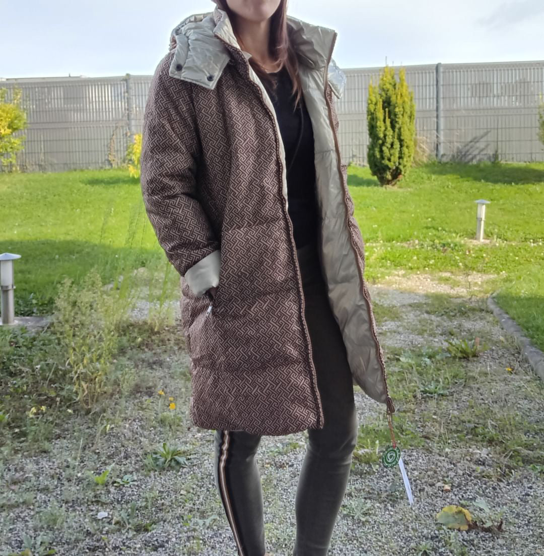 Woman wearing a long reversible brown quilted waterproof coat outdoors, Le Petit Placard