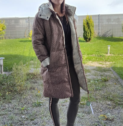 Woman wearing a long reversible brown quilted waterproof coat outdoors, Le Petit Placard