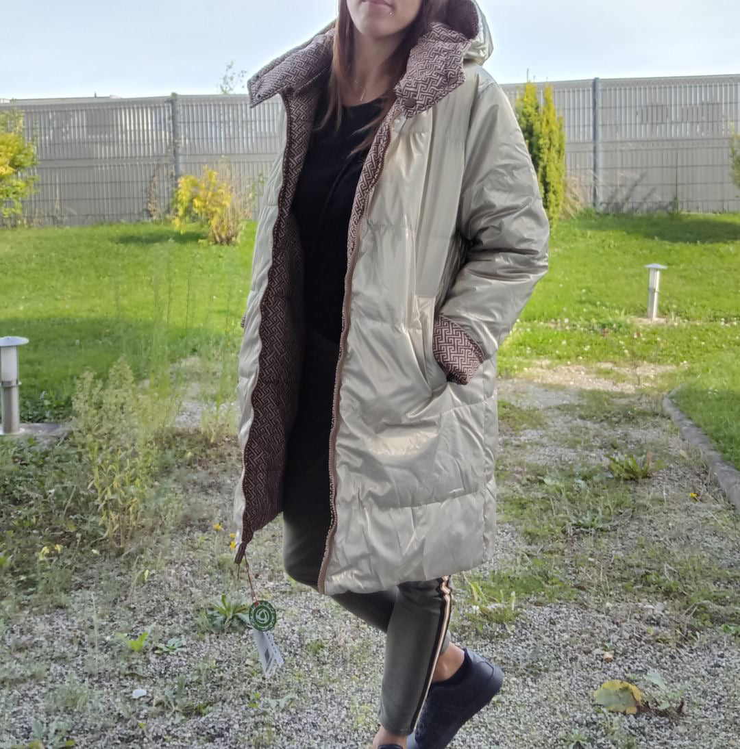 Woman wearing a long reversible gold and brown quilted raincoat by Escandelle outdoors