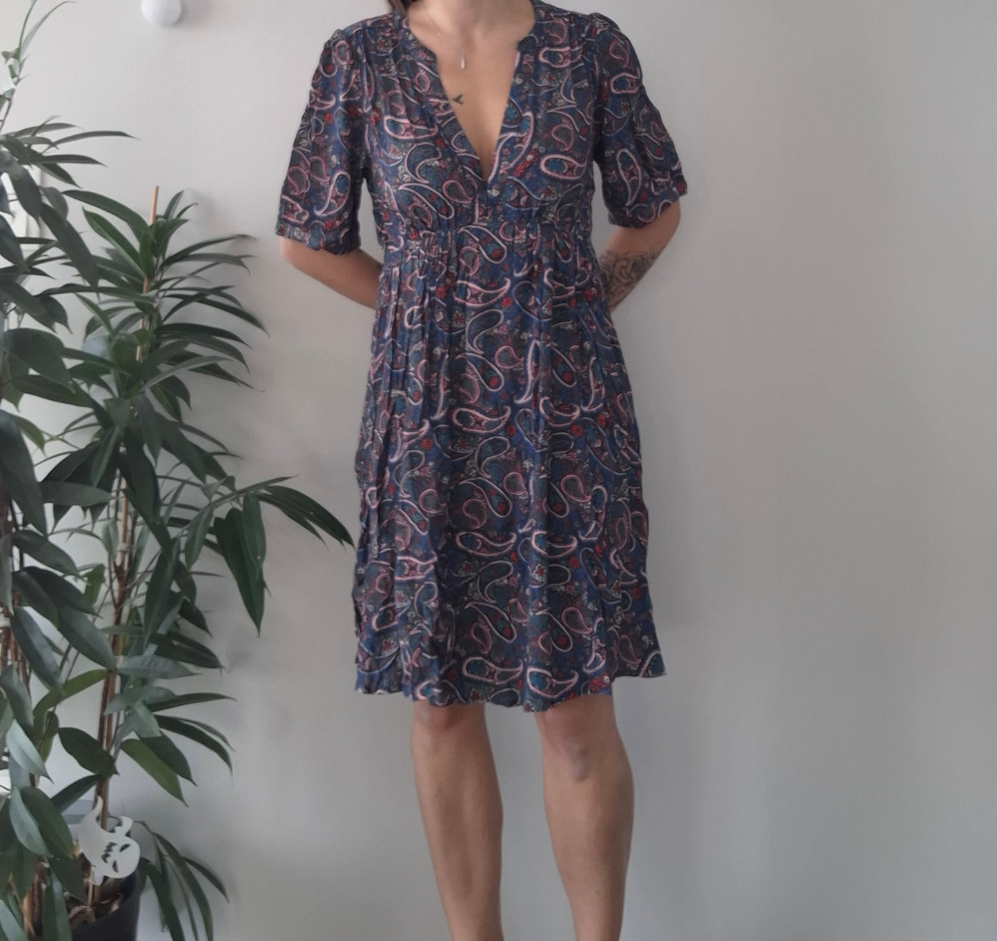 Woman wearing a paisley print dress, Le Petit Placard fashion accessory, indoor setting