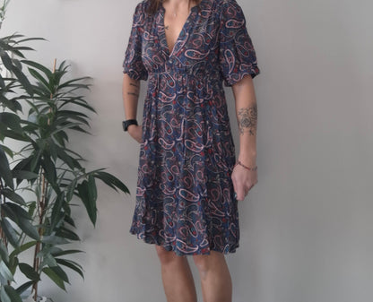 Woman wearing a paisley print dress indoors, Le Petit Placard fashion style, plant decor nearby