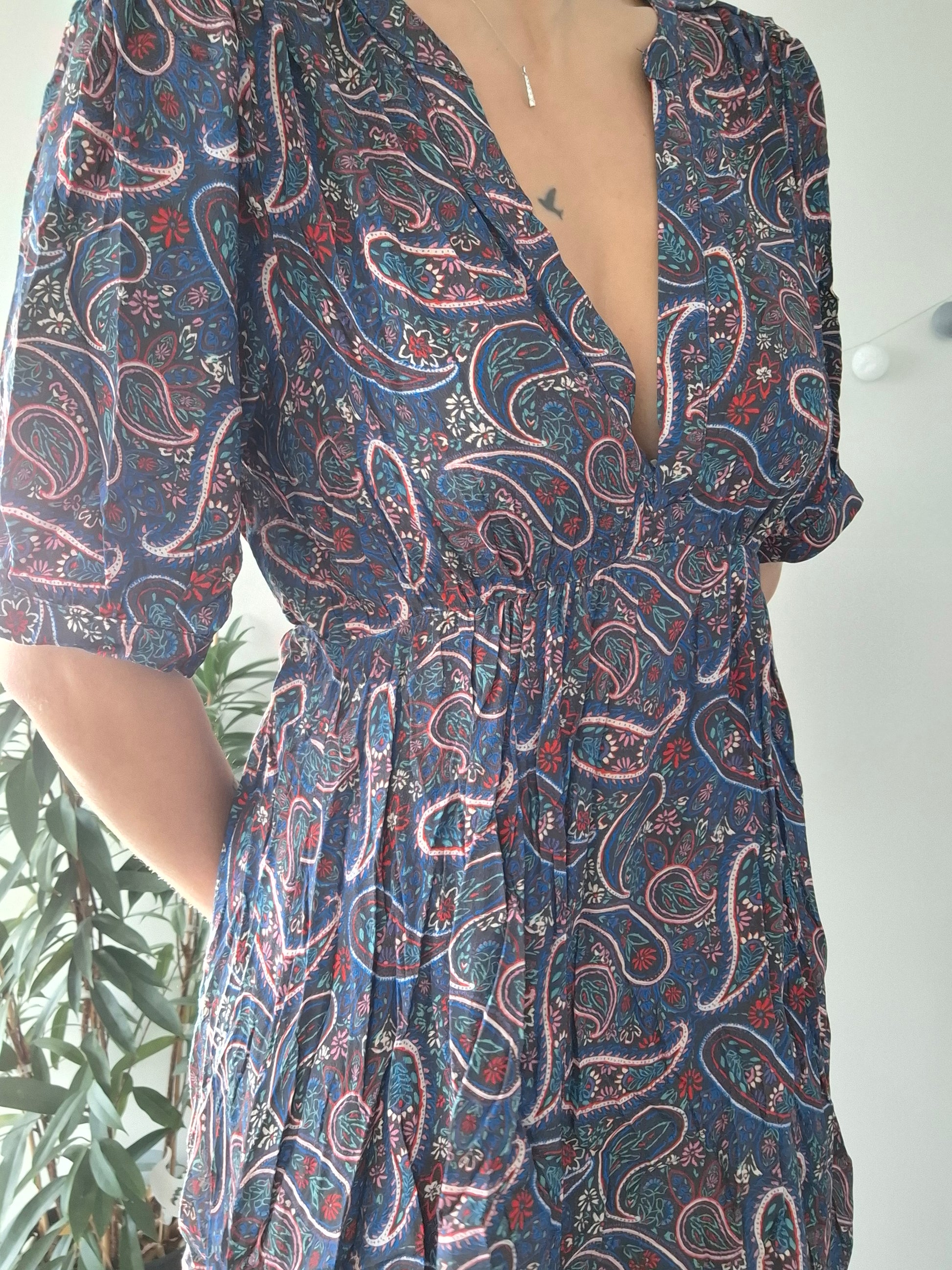 Woman wearing a blue paisley print dress, with floral details, from Le Petit Placard.