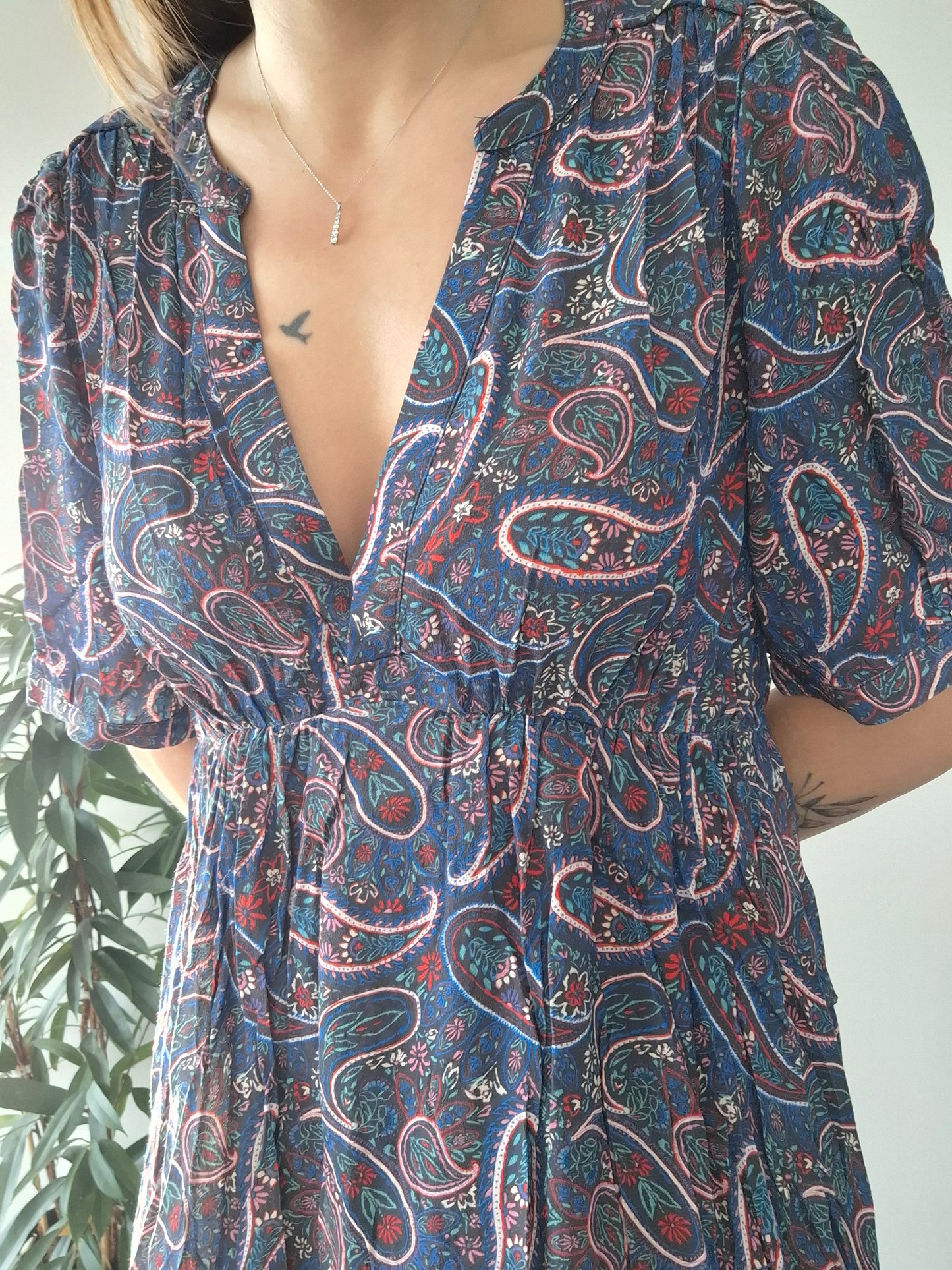 Woman wearing a paisley print dress from Le Petit Placard, close-up front view indoors