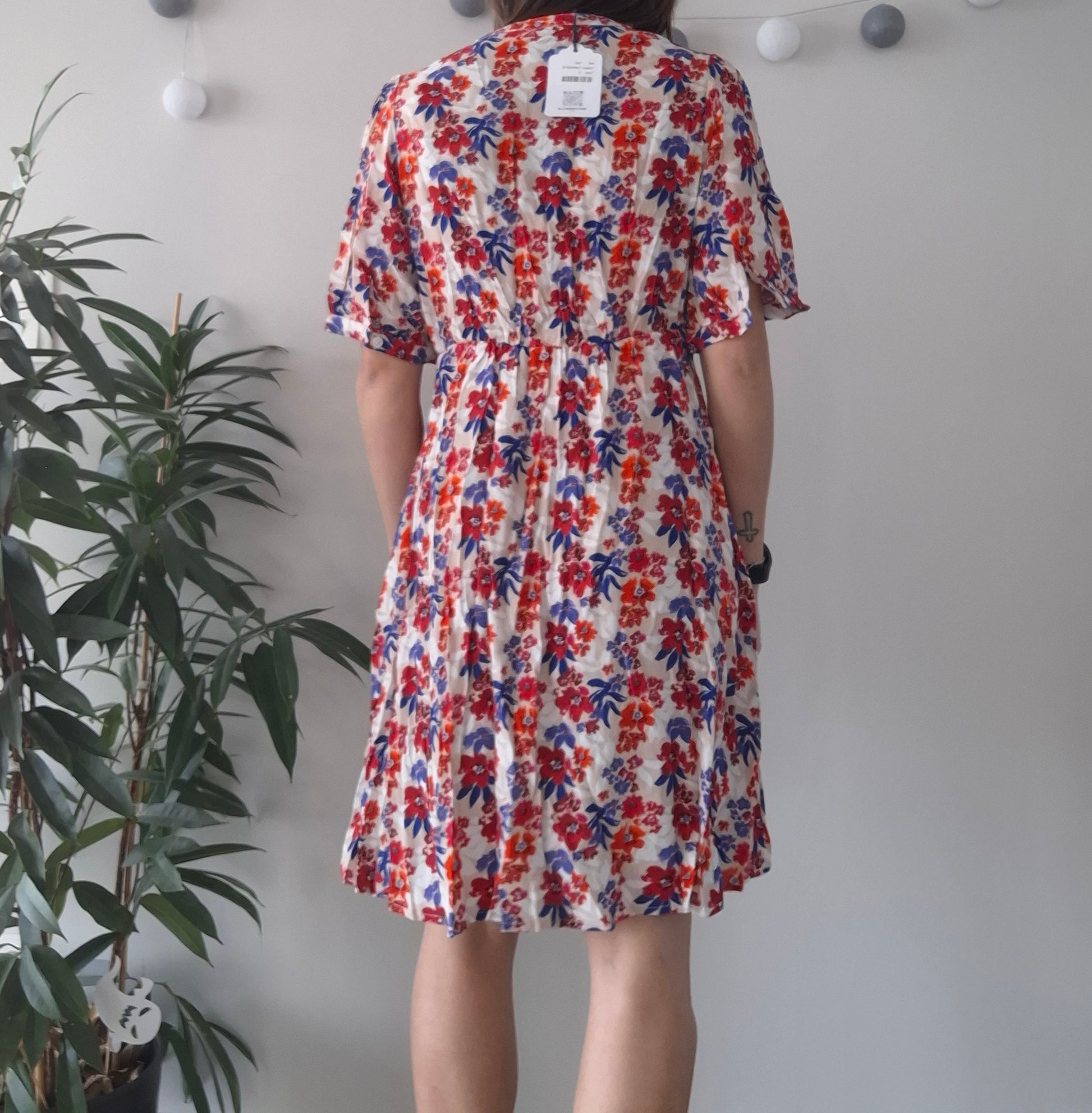 Woman in floral summer dress with red and blue print, Le Petit Placard fashion, indoor setting