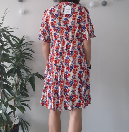Woman in floral summer dress with red and blue print, Le Petit Placard fashion, indoor setting