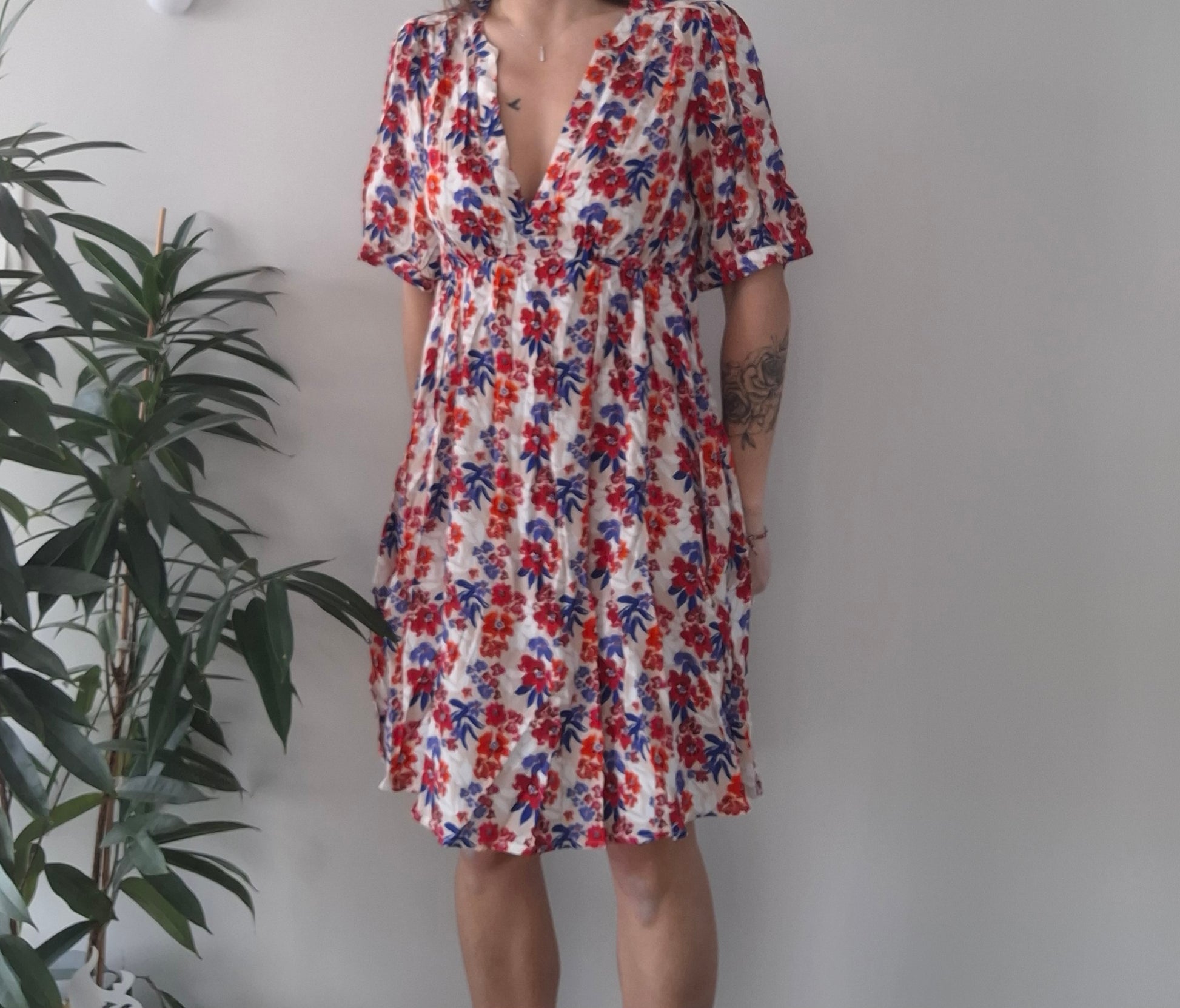 Woman wearing a floral summer dress with red and blue flowers at Le Petit Placard