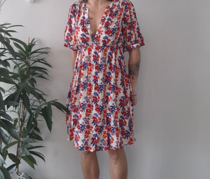 Woman wearing a floral summer dress with red and blue flowers at Le Petit Placard