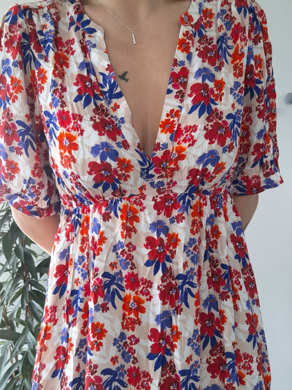 Woman wearing floral dress with red, blue, and orange prints, Le Petit Placard style