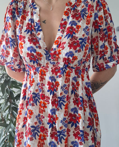 Woman wearing a colorful floral dress with red, blue, and orange patterns from Le Petit Placard