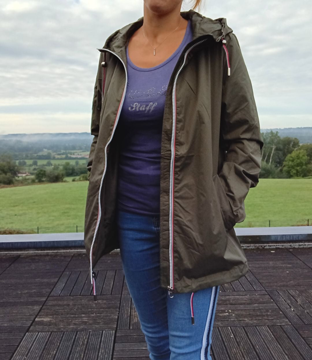 Femme portant un imperméable kaki Laura Jo et un jean bleu à l'extérieur, style Le Petit Placard.