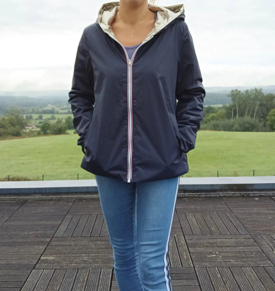 Imperméable réversible court bleu marine doré femme Laura Jo Mi Saison, porté en extérieur sur fond de paysage bucolique.