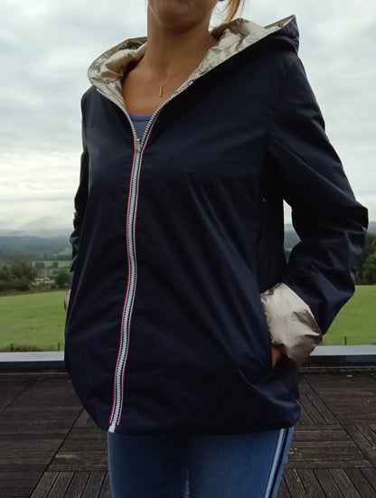 Imperméable réversible court bleu marine doré femme, fermeture éclair capitaine dorée, détails poignets beige clair, porté en extérieur.