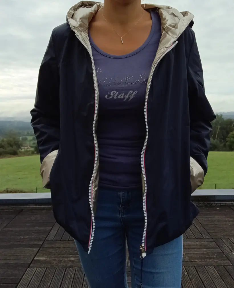 Imperméable réversible court bleu marine doré femme Laura Jo Mi Saison porté en extérieur, capuche, zips visibles, manches retroussées.