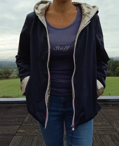 Imperméable réversible court bleu marine doré femme Laura Jo Mi Saison porté en extérieur, capuche, zips visibles, manches retroussées.