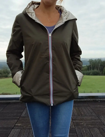 Imperméable réversible court kaki doré femme Laura Jo Mi-Saison portée en extérieur, avec capuche et zips contrastés, jeans bleus.