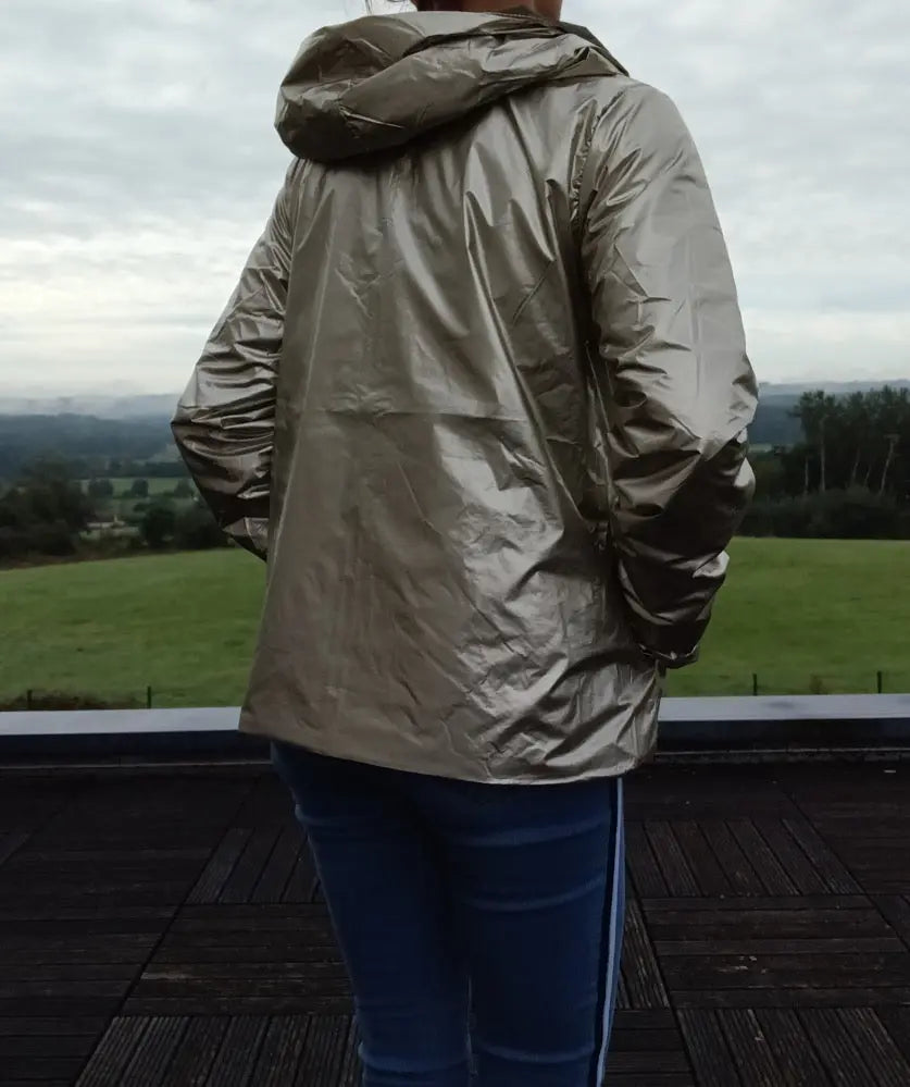 Imperméable réversible court kaki doré femme, vue arrière sur une personne debout sur une terrasse avec paysage verdoyant.