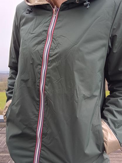 Veste imperméable réversible vert forêt / doré, coupe courte avec capuche, fermeture éclair centrale à rubans tricolores, doublure sombre, manches pliées, portée en plein air. Laura Jo