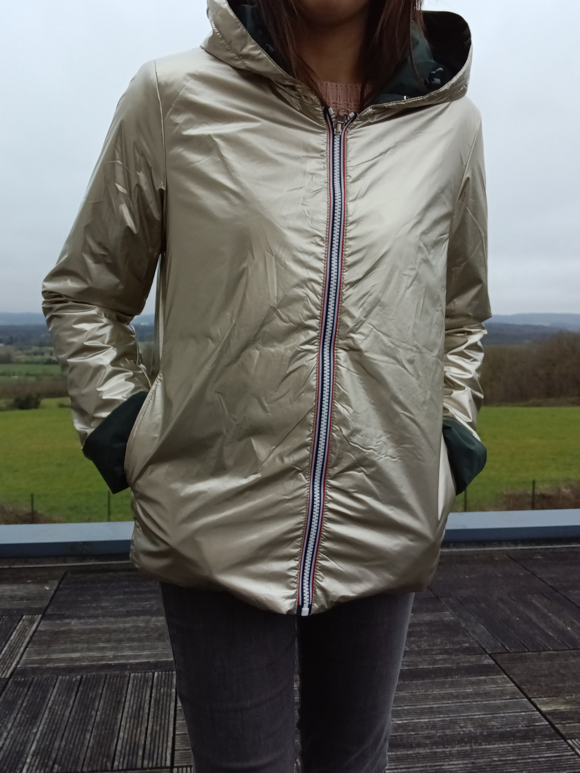 Imperméable réversible Laura Jo couleur vert forêt/doré, fermeture zippée centrale sur fond beige clair, capuche et poches côté, garnissage ouate mi-saison.