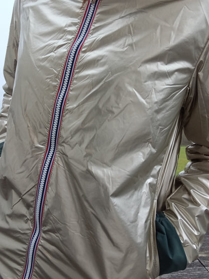 Veste imperméable réversible doré, coupe courte avec capuche, fermeture éclair centrale, doublure sombre, manches pliées, portée en plein air. Laura Jo