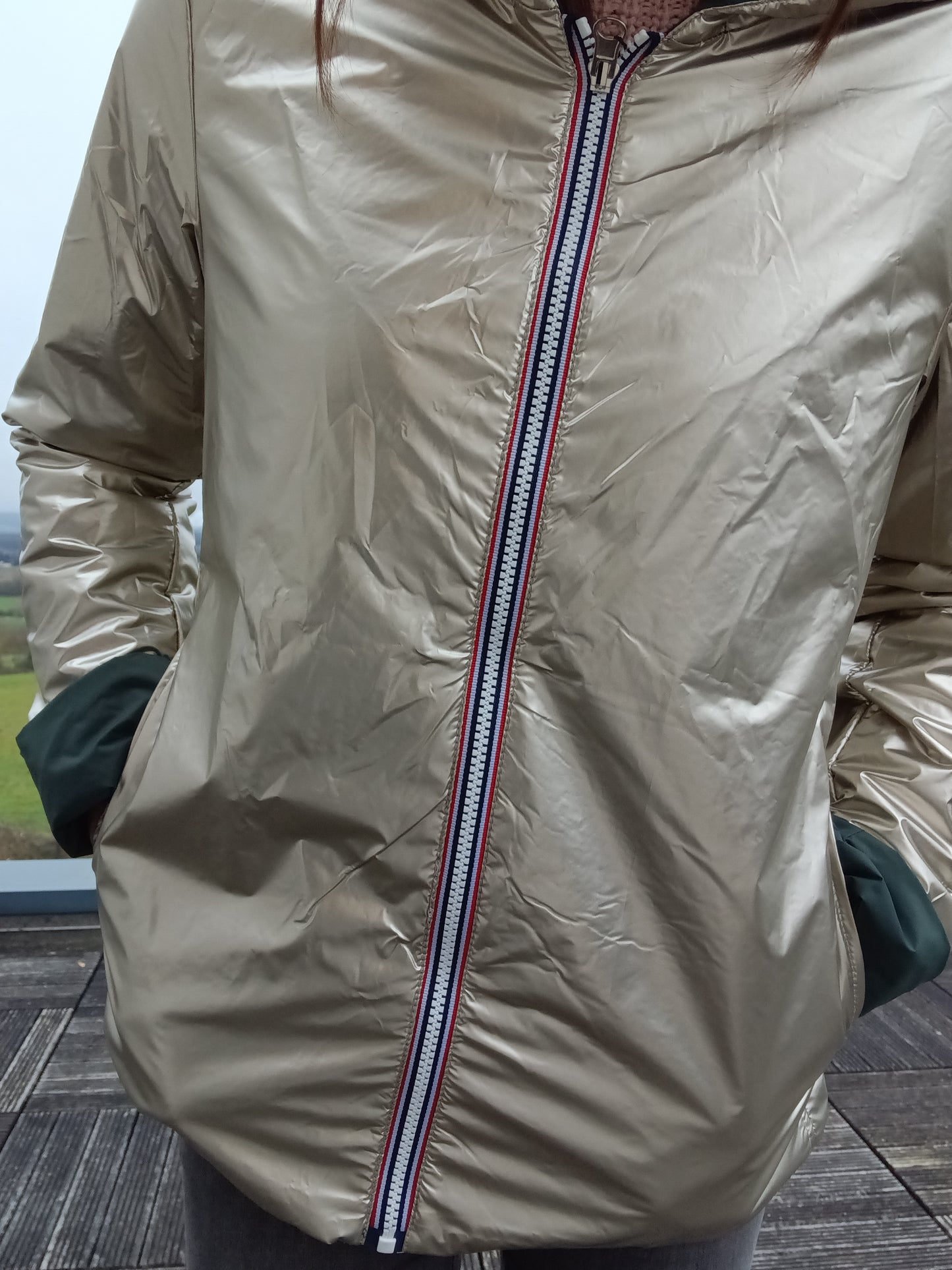 Veste imperméable réversible vert forêt / doré, coupe courte avec capuche, fermeture éclair centrale à rubans tricolores, doublure sombre. Laura Jo
