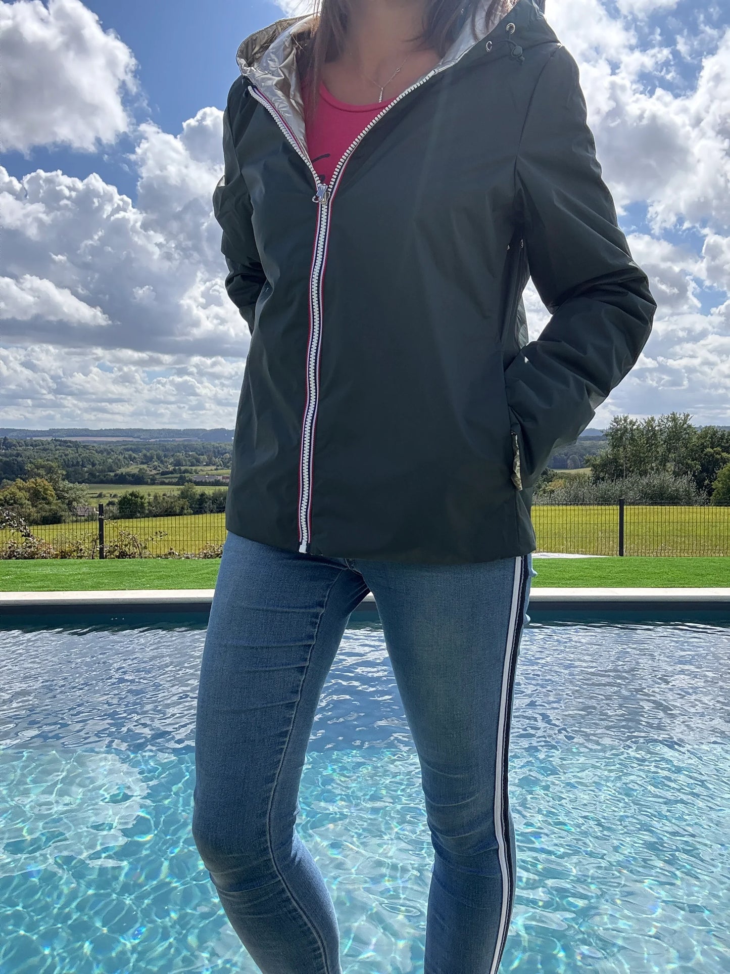 Imperméable réversible Laura Jo, court, garnissage ouate mi-saison, vert forêt/doré, porté en extérieur près de la piscine.