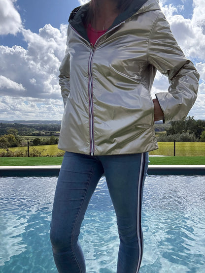 Laura Jo imperméable réversible court en garnissage ouate, couleur vert forêt et doré, veste légère portée près d’une piscine en extérieur.