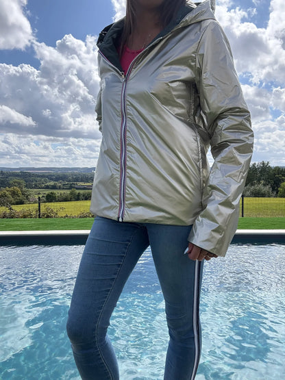 Laurie Jo imperméable réversible court en garnissage ouate, couleur vert forêt/or médaillé doré, porté avec jean près d’une piscine en plein air.