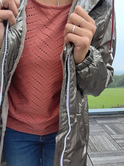 Woman wearing bronze Laura Jo raincoat over pink lace top, outdoors on wooden terrace