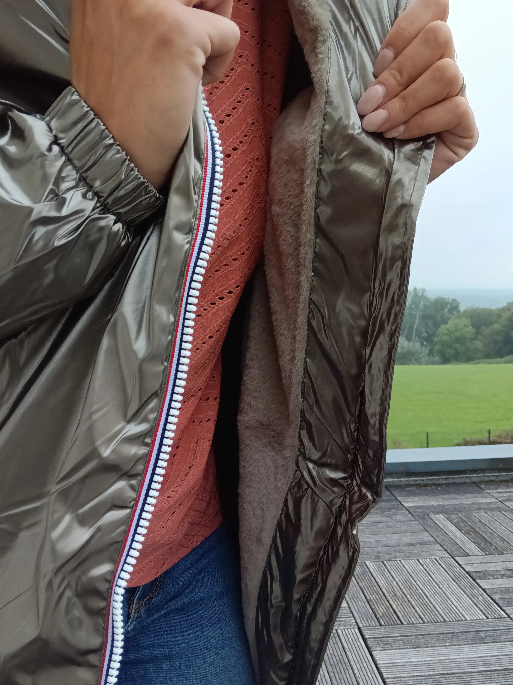 Woman holding open bronze Laura Jo raincoat with soft lining, worn over lace top, outdoors