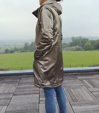 Woman in bronze Laura Jo raincoat from Le Petit Placard, standing outdoors on a terrace