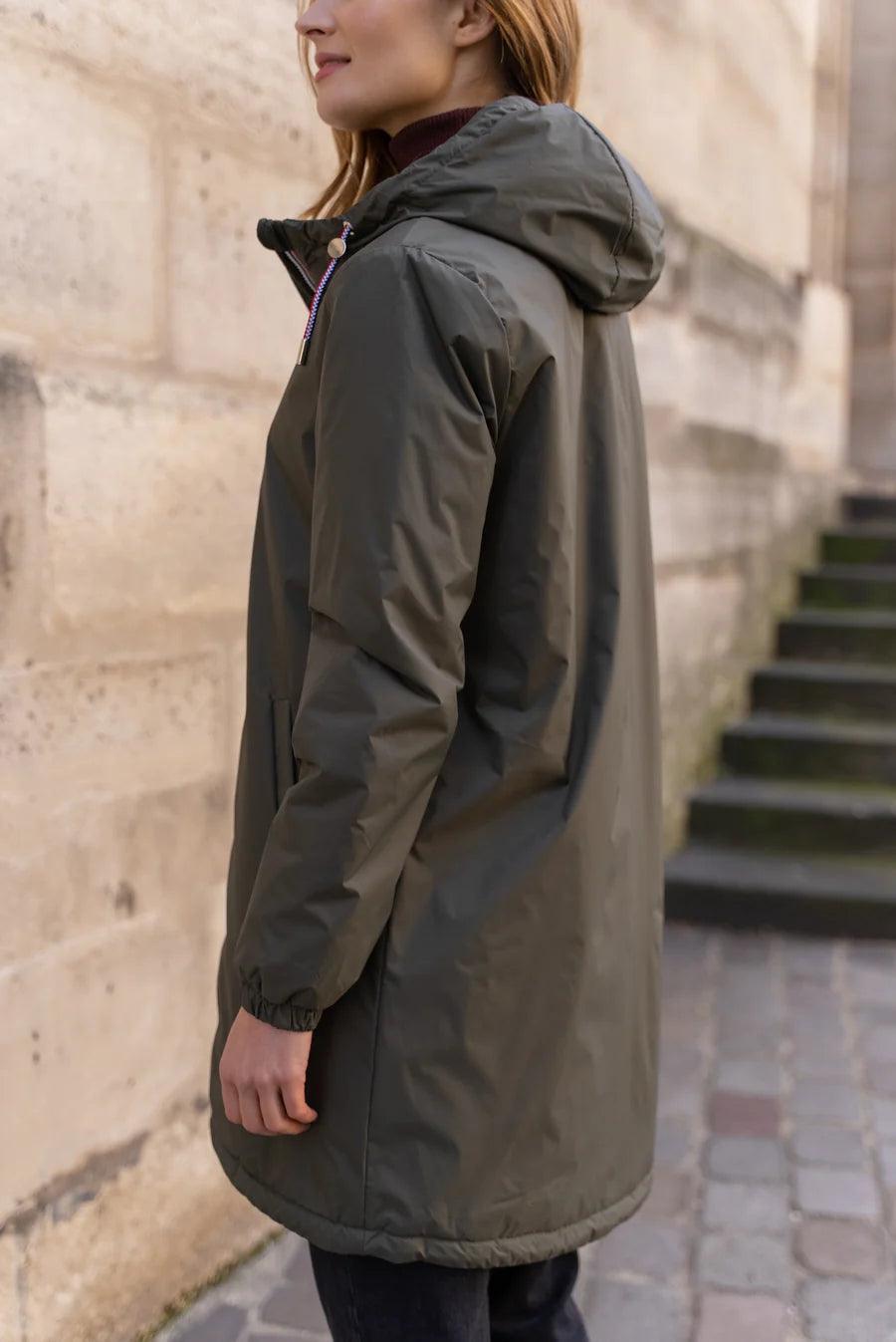 Woman wearing Laura Jo khaki long raincoat with hood and tricolour cord, outdoors