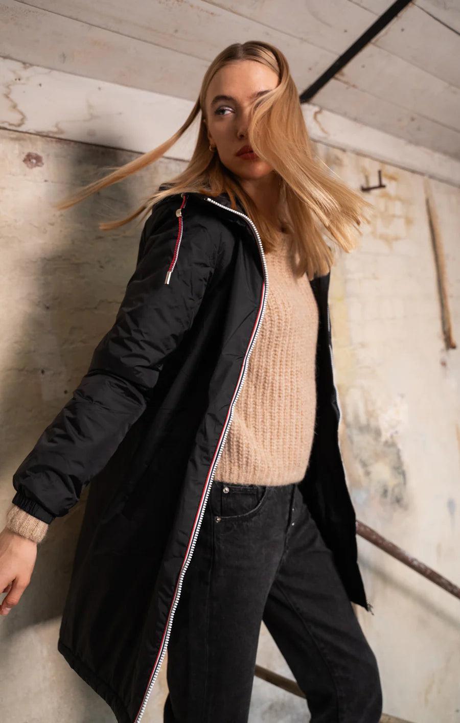 Woman wearing a Laura Jo black waterproof coat with faux fur trim and tricolor cord, casual style