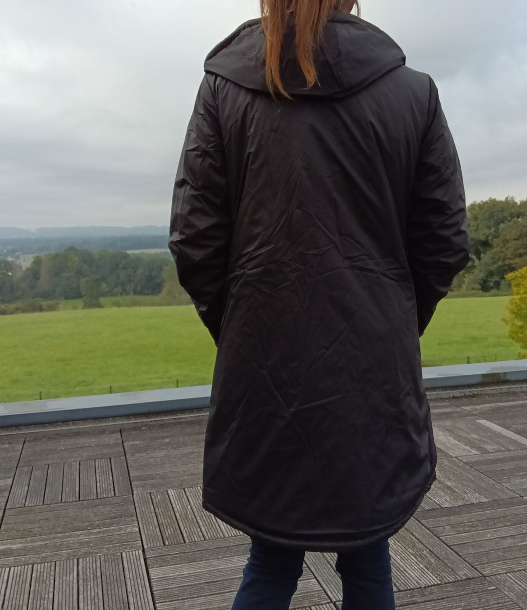 Woman wearing a long black Laura Jo waterproof coat outdoors, Le Petit Placard