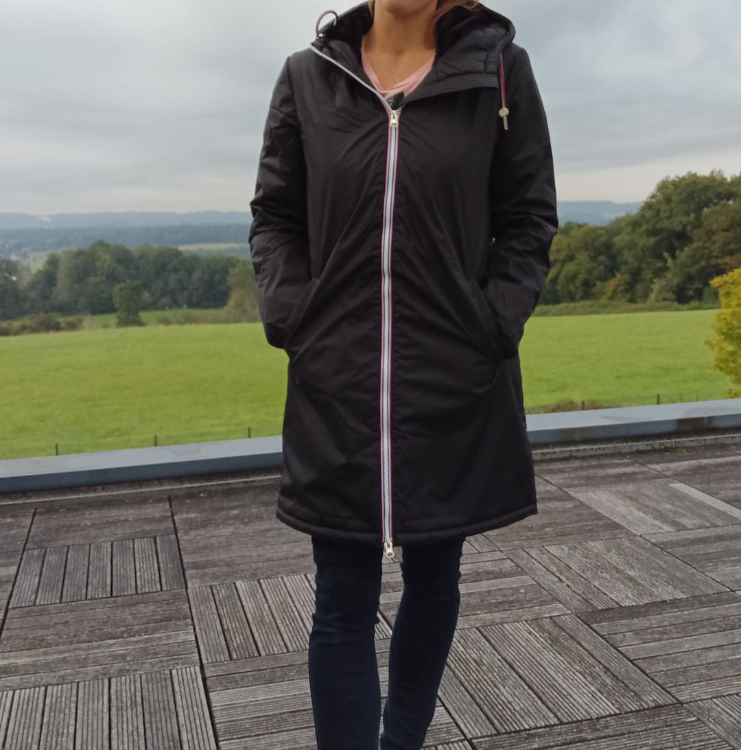 Woman wearing Laura Jo black long raincoat with tricolor zipper, outdoor setting, Le Petit Placard