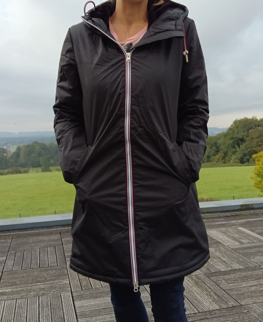 Woman wearing a Laura Jo black raincoat with tricolor zipper outdoors, Le Petit Placard