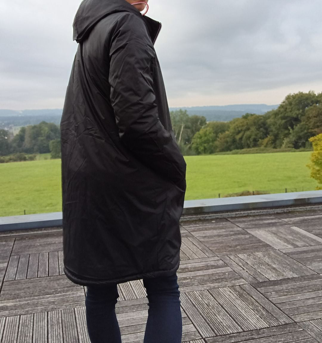 Person wearing a black Laura Jo waterproof long coat outdoors, Le Petit Placard style