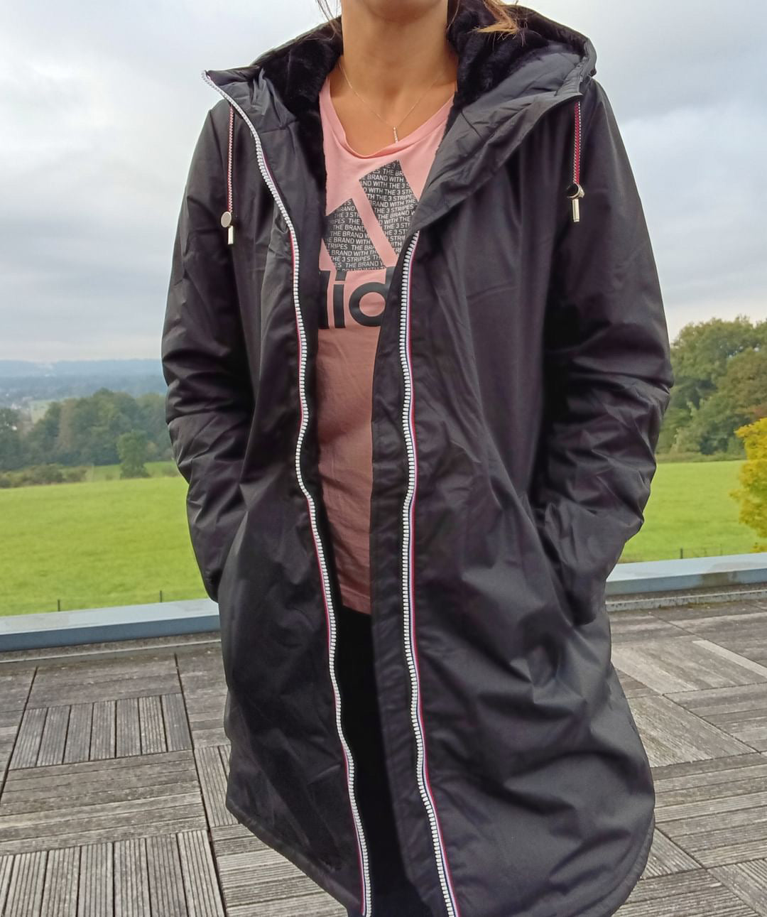 Woman wearing black Laura Jo long raincoat with tricolor cord, outdoor setting, Le Petit Placard