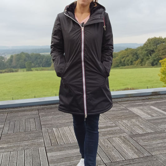 Woman wearing Laura Jo black long waterproof coat with tricolor cord, outdoors on terrace
