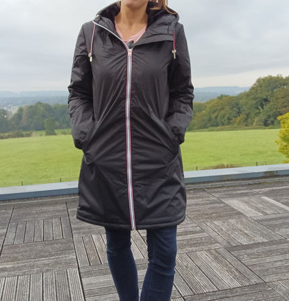Woman wearing black Laura Jo long raincoat with fur lining and tricolor zipper, outdoors
